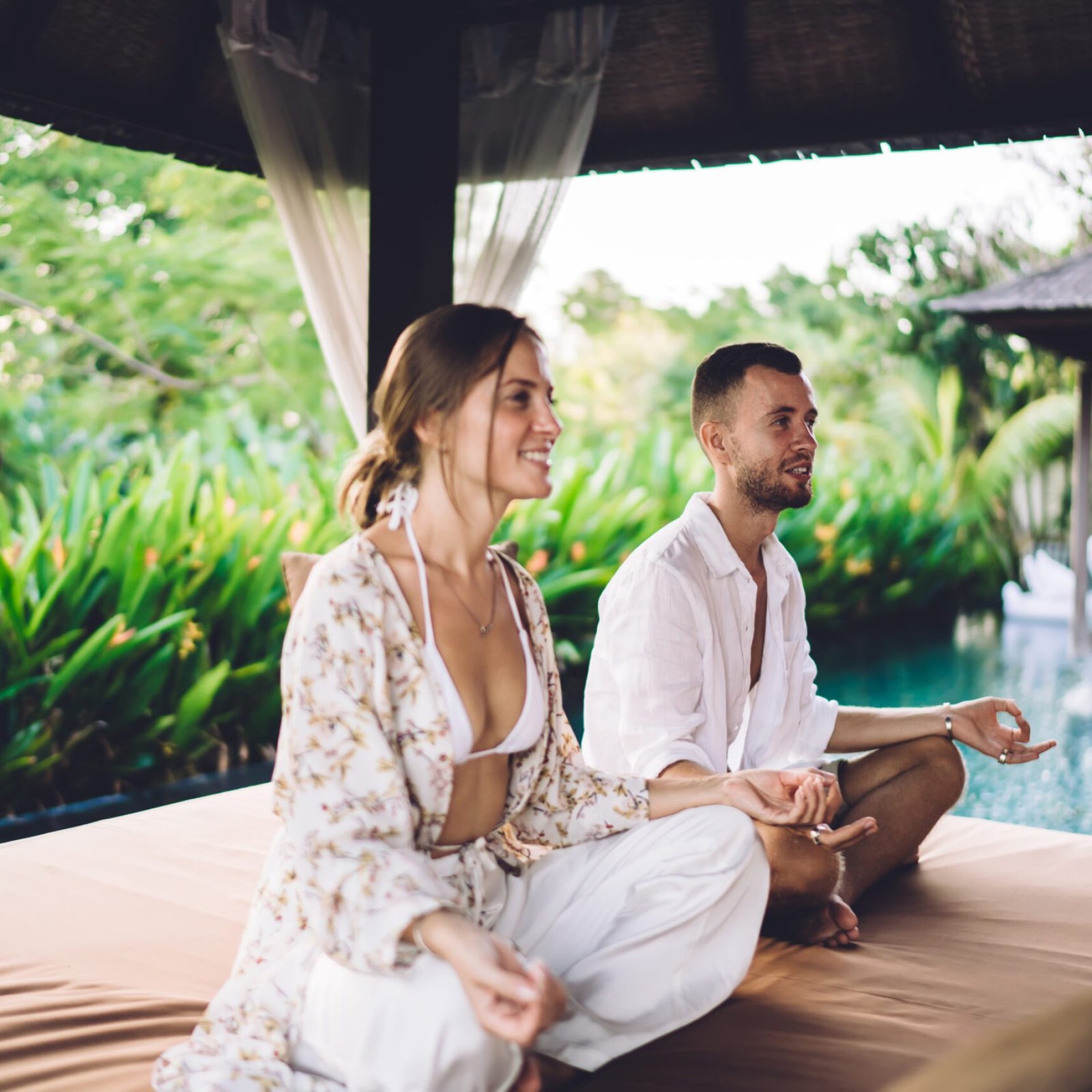 Happy male and female couple smiling during together mediation on yoga practice, cheerful Caucaisan persons relaxing in hatha pose enjoying time for searching zen and chakra at villa terrace